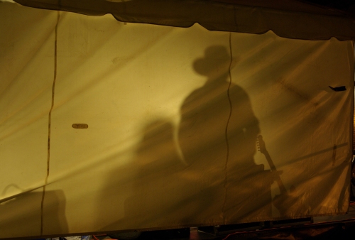 Performers reduced to silhouettes at night through the canvas tent walls.