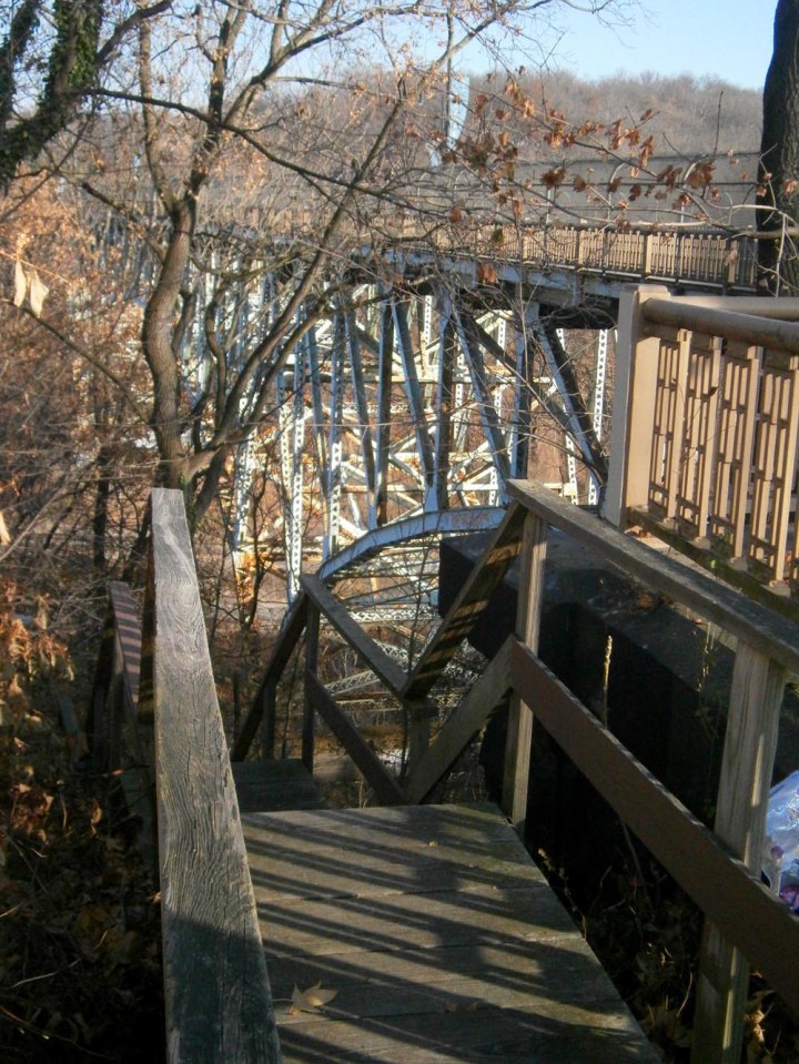 Photo of wooden steps next to arched bridge.