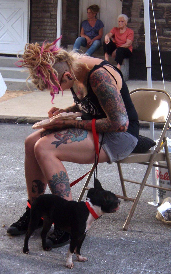 tattood woman with dog working on art project